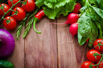 Fresh ingredients for cooking in rustic setting: Salad, radish, Onion, corn, tomatoes, garlic, carrots, cucumber, pepper, eggplant, basil, rosemary