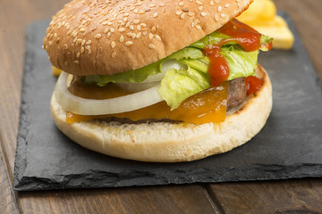 Closeup of appetizing homemade burgers served on stone board with fries.