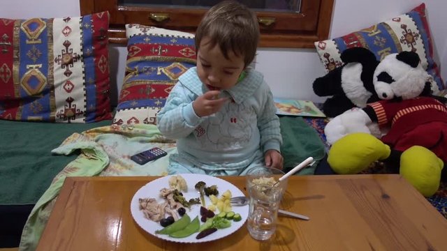 Child is eating broccoli at the dinner table