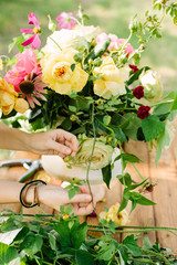 wedding, celebration, floral design, spring, nature concept - woman's hands fixing few stalks in great multicolored bouquet made of ballet pink peonies, english roses and avalanches