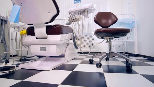 dentist office with two dental chairs. Contemporary empty dental office with dental chair and equipment. black and white tile in a checkerboard pattern on the floor