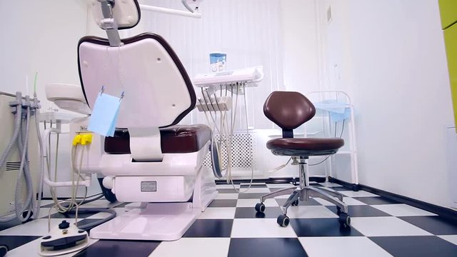 Dental clinic: room with dental chair and medical equipment. black and white tile in a checkerboard pattern on the floor