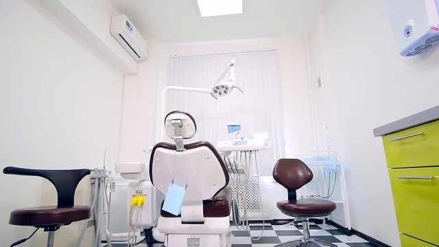 Workplace of dentist with dental unit and chair closeup. black and white tile in a checkerboard pattern on the floor