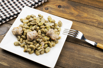 From above plate with cooked beans and sausage served on wooden table. Horizontal studio shot.