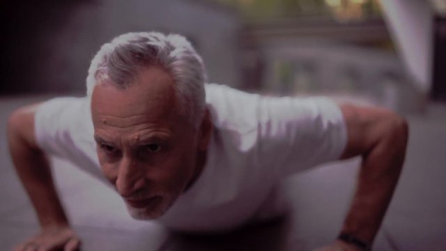 Persevering aged man doing push ups outdoors