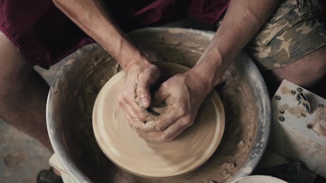 The hands of a potter, creating an earthen jar on the circle, close-up, hands on circle with clay