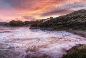 Fototapeta premium Rough seas at sunset on Caswell Bay, one of the most popular, easily accessible and closest beaches to Swansea City, on the Gower peninsula, South Wales, UK