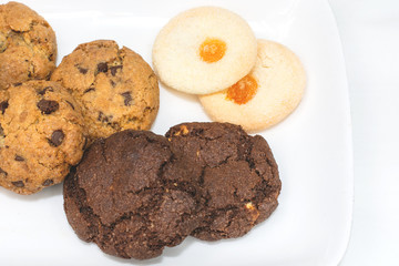 Top view of a plate of oatmeal chocolate, shortbread cookies on a white background