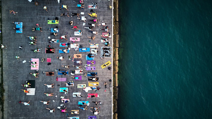 top view of large group of people practice yoga on sea coast