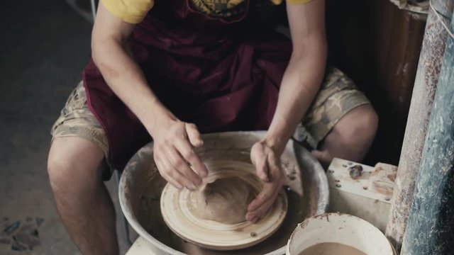 The hands of a potter, creating an earthen jar on the circle, close-up, hands on circle with clay