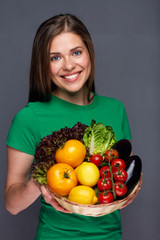 Fototapeta na wymiar Smiling woman holding basket with vegetables.