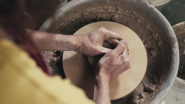Hands of the master potter and vase of clay on the potter's wheel close-up. Master crock man. Twisted potter's wheel.