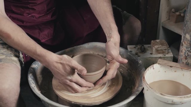 Hands of the master potter and vase of clay on the potter's wheel close-up. Master crock man. Twisted potter's wheel.