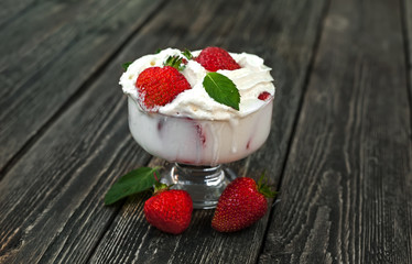 Strawberries with cream in a glass on a wooden table
