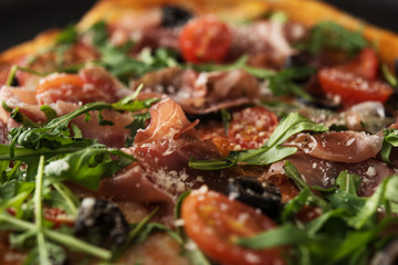 Traditional pizza with prosciutto and arugula