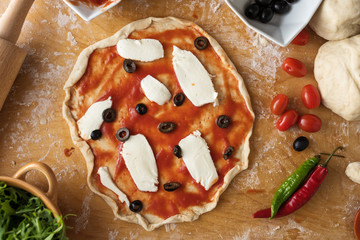 Prosciutto pizza preparation on wooden background