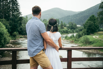 man with woman stands on the bridge across the river