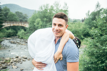 man taking woman on his shoulder near mountains river