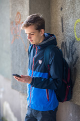 The teenager is holding a phone in his hand