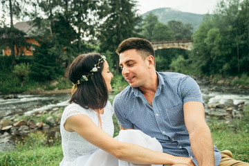 couple sits near mountain river