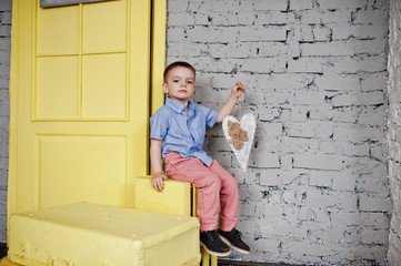 Portrait of a small cute boy posing in the official clothing in the studio with yellow boxes and...