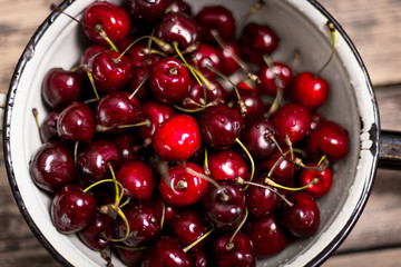 Cherry in enameled metal colander on wood table