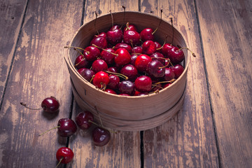 Cherry in wooden bowl on wood table