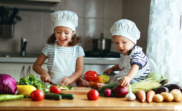 Healthy eating. Happy children prepares  vegetable salad in kitchen.