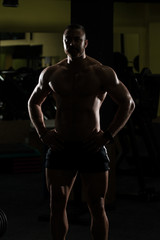 Fototapeta na wymiar Siluet Muscular Man Flexing Muscles In Gym