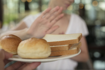 Gluten intolerance and diet concept. Woman refuses to eat white bread. Selective focus on bread