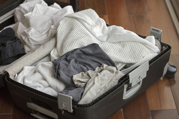 The suitcase full of used and dirty clothing before going home from a vacation trip.