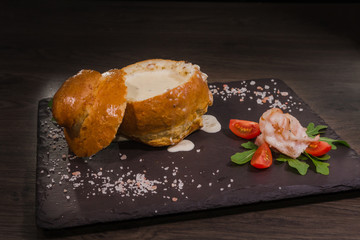 Fresh pea soup in a Bread Bowl, on a wooden board with salt and papper