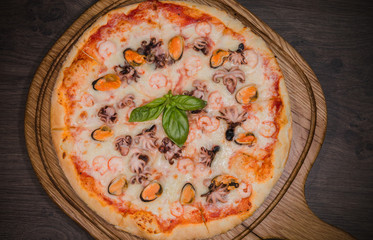 Hot piece of pizza with melted cheese on a rustic wooden table