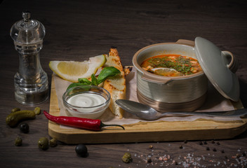 Soup on a wooden background with white bread and sauce