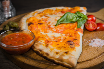 Hot piece of pizza with melted cheese on a rustic wooden table