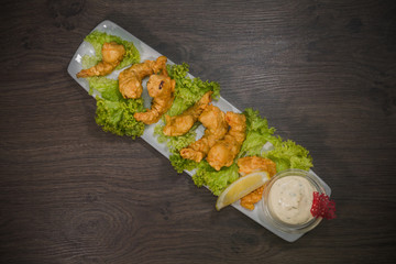 Fried prawns on a plate with sauce and on a wooden background