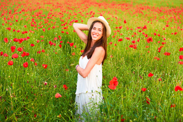 Naklejka na ściany i meble A happy woman in the field of red poppies