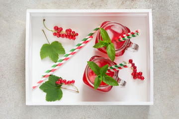 Summer homemade lemonade with red currant, ice and mint on rustic table, with white tray. Copy space, top viewleaf.