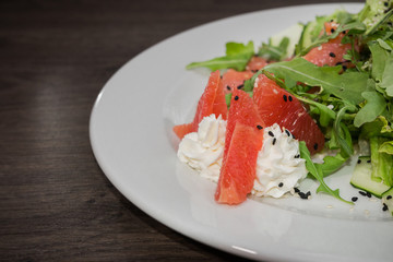 Meat of trout on a plate with vegetables and grapefruit