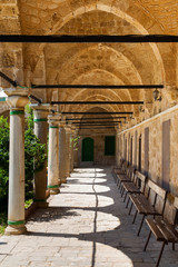 Columned portico with Stone Pillars and  wooden Benches in Mosque in Acri Akko Israel