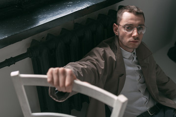 Fototapeta premium A lonely handsome guy in a raincoat and glasses with different moods