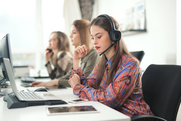 Portrait of young woman with hands-free device working in a customer support service