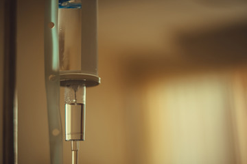 Close up saline solution drip for patient and infusion bottle with IV solution in patient room in hospital.