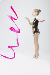 Sport Concepts. Little Caucasian Female Rhythmic Gymnast In Professional Competitive Suit Doing Artistic Ribbon Spirals Exercises in Studio Against White.
