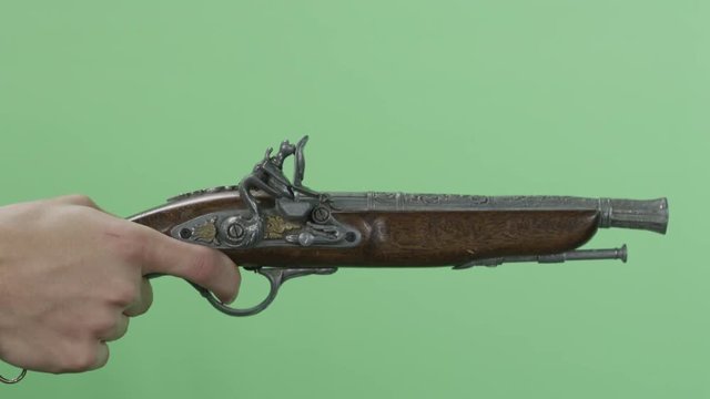 Man with an old pistol. Vintage antique flintlock pistol isolated on green screen. Man's hand shoots from the vintage of the gun