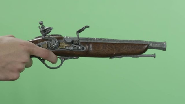 Man with an old pistol. Vintage antique flintlock pistol isolated on green screen. Man's hand shoots from the vintage of the gun