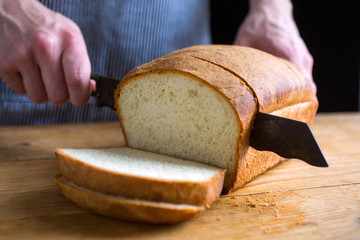 Hands of man slicing white bread
