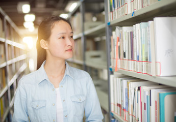 Portrait of a smiling young student reading a book in a library