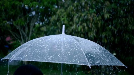 Close-up on umbrella with rain falling in slow motion shot