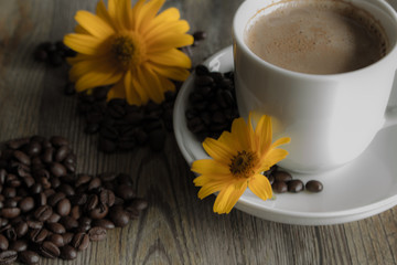 Filiżanka kawy z żółtymi kwiatami w tle.